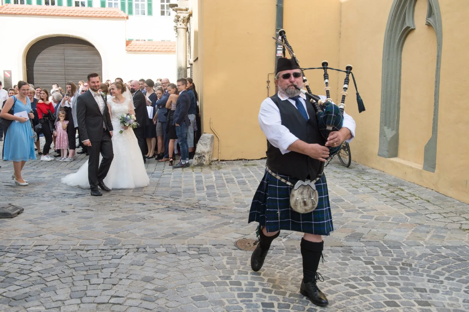 Udo Zahlauer in schottischer Kleidung mit Kilt, Weste und Krawatte spielt Dudelsack vor der Hochzeitsgesellschaft
